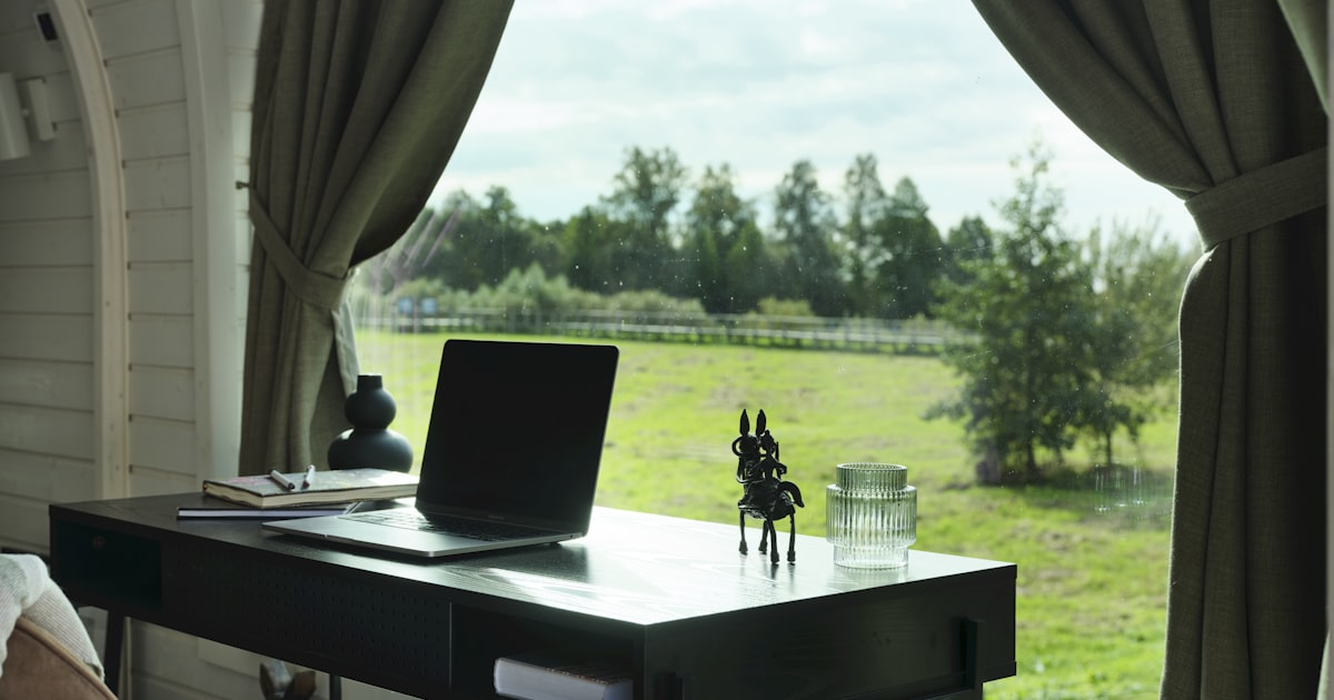 A laptop on a desk inside a garden cabin with a view over green countryside — the kind of setup that needs its own access point